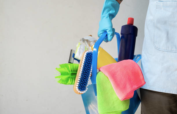 A person wearing a blue glove holding a caddy filled with various cleaning supplies for Infinite Cleaning in Minneapolis, MN.