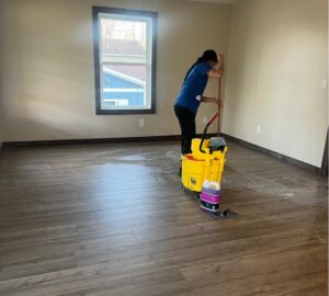 A professional cleaner from Clean Corp Indiana mopping a floor in an empty room of a house in Bloomington, IN.
