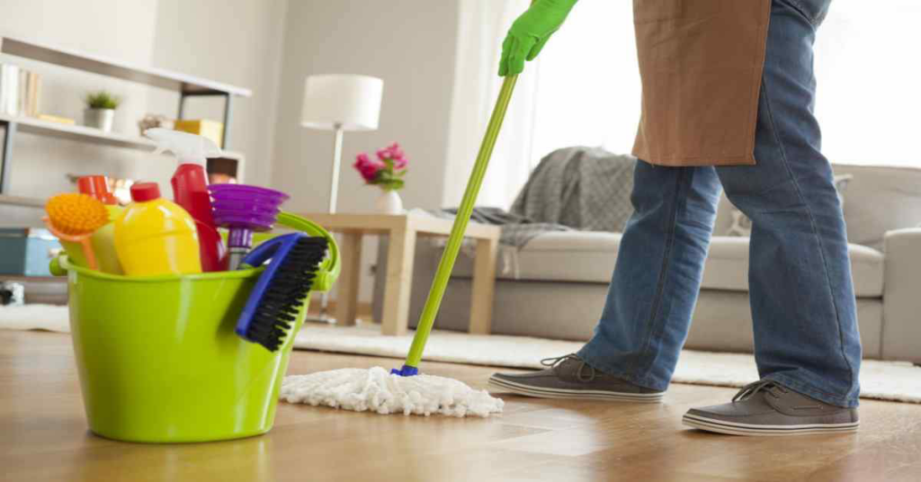 A person in green gloves mopping a clean floor with a bucket of cleaning supplies at Sparkle & Shine of Iowa in Urbandale, IA.