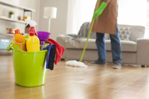 A person mopping a wooden floor in a clean living room, with a bucket of cleaning supplies in the foreground, by Full Circle Commercial Cleaning in Scottsdale, AZ.