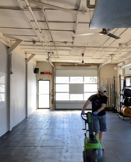 A person operating a professional floor scrubber for Clean Sweeper Cleaning Services in Melrose, MA