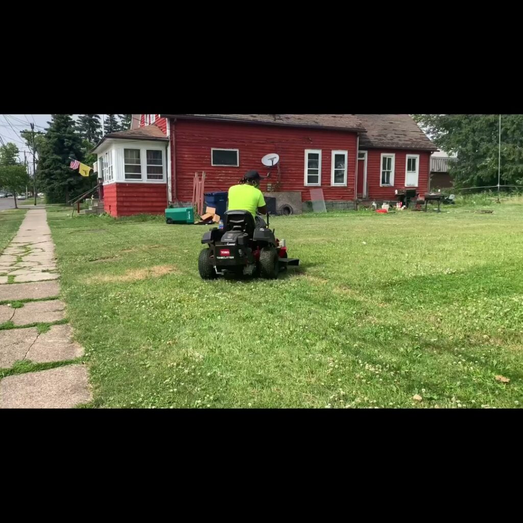 A person operating a snow blower to clear a snowy driveway, a service by Knight's Landscaping & Snow Removal in Buffalo, NY.