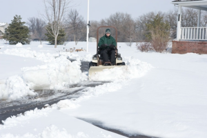 A person plowing snow from a residential driveway for Lawn Performance, LLC in Albany, GA