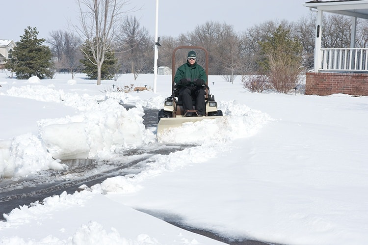 A person plowing snow from a residential driveway for Lawn Performance, LLC in Albany, GA