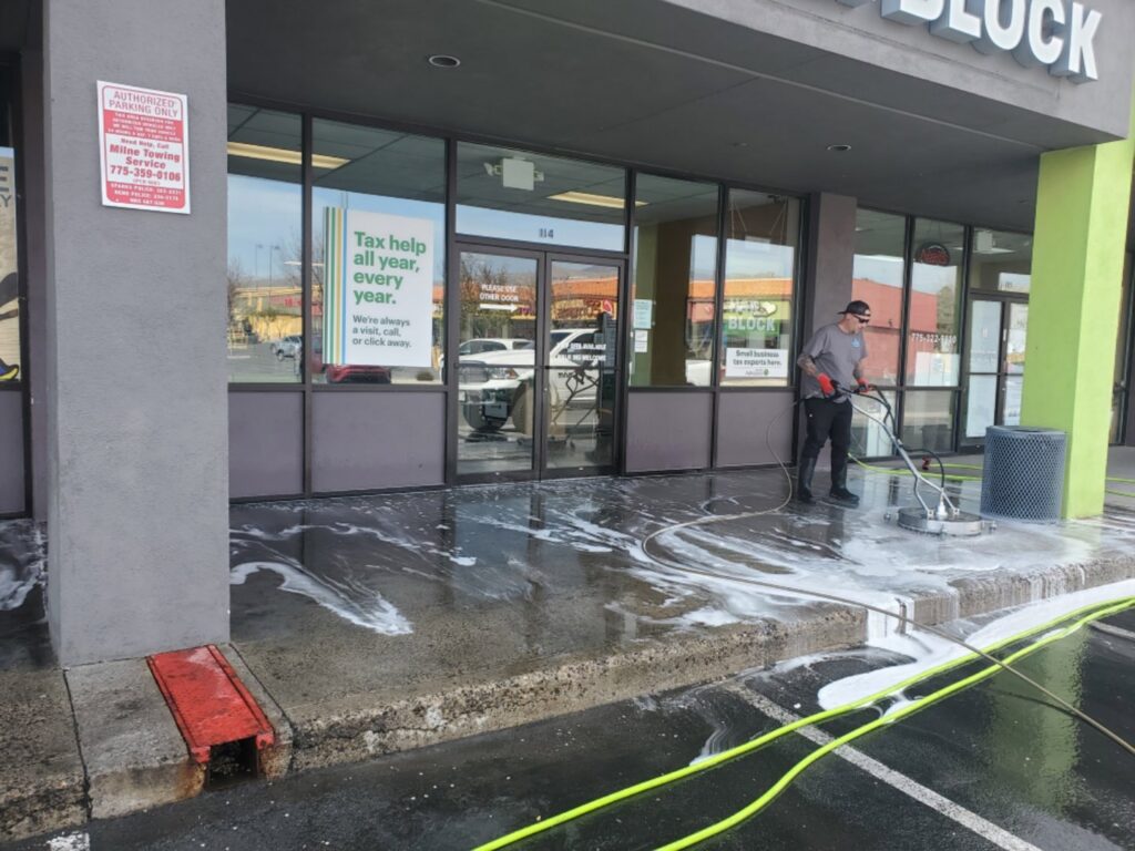 A person pressure washing a commercial sidewalk in front of a business by EB Restorations & Cleaning Services in Sparks, NV