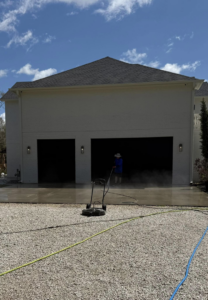 A person using a surface cleaner to pressure wash a residential driveway for Hot Tech Pressure Washing in Gulfport, MS.