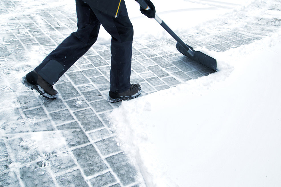 A person shoveling snow from a paved area, demonstrating manual snow removal services by JC Snow Management in Mount Vernon, NY