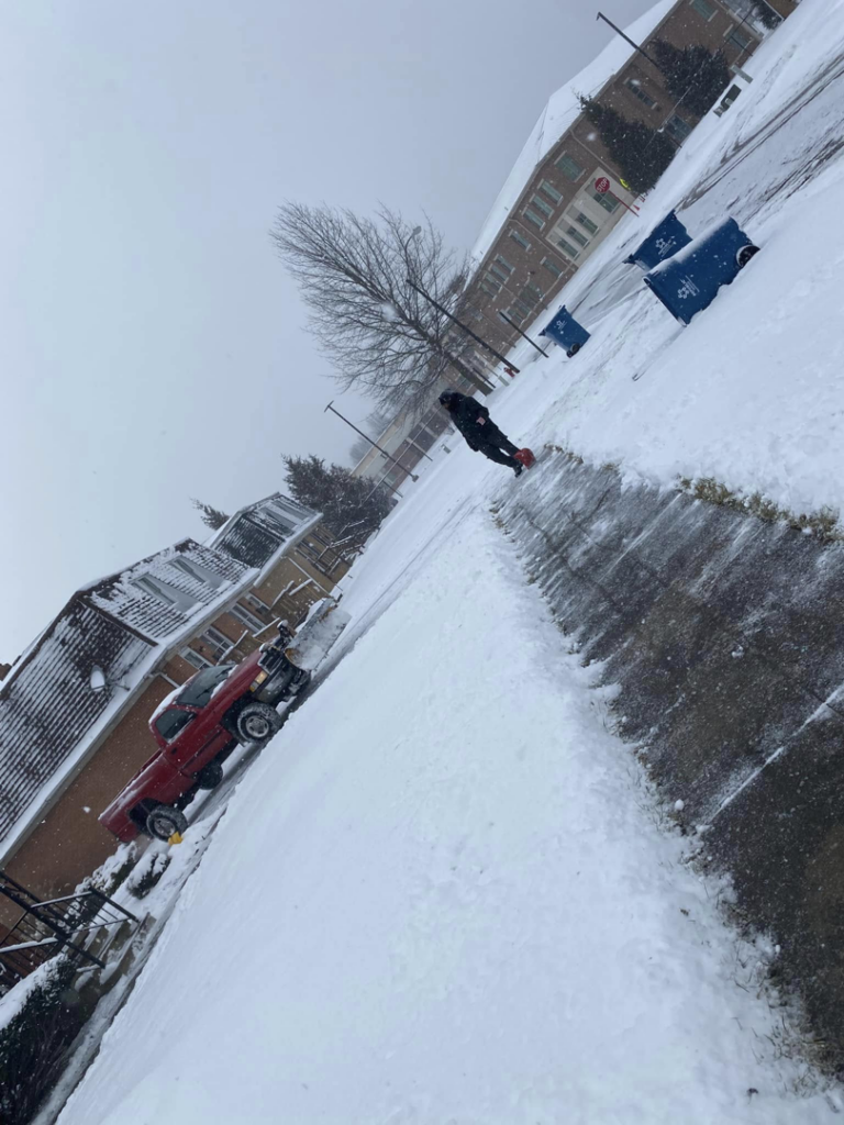 A person actively shoveling snow from a sidewalk, providing snow removal services by Limitless Home And Lawn Renovations in Youngstown, OH.