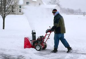 A person using a snow blower to clear a residential driveway for Haynes Snow Removal & Lawn Maintenance in Madison, WI.