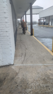A person spreading ice melt on a commercial sidewalk for snow removal by Kickin Grass Lawncare LLC in Springdale, AR.
