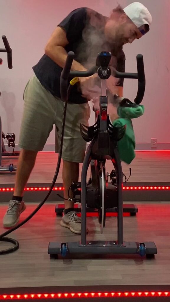 A person steam cleaning a spin bike at a gym for Clean Sweeper Cleaning Services in Melrose, MA