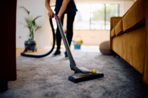 A person vacuuming a carpet in a living room, showcasing house cleaning services by ABF Professional Cleaning Inc in Jackson, WY.