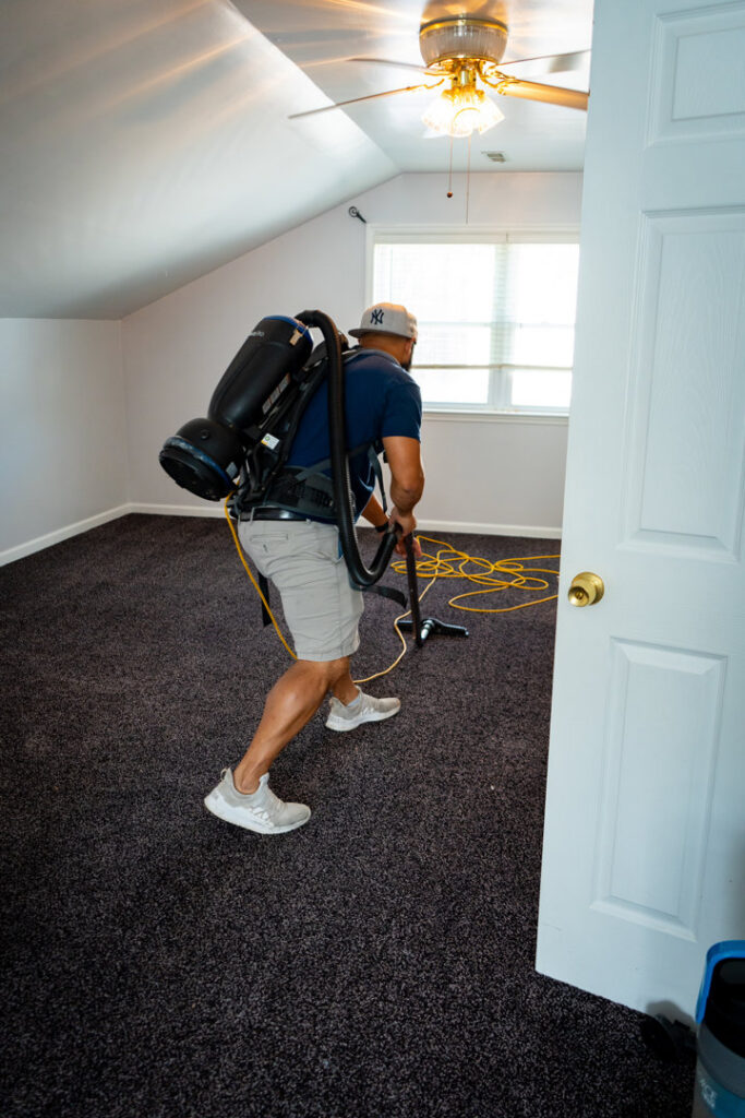 A cleaner from Southern Royalty Cleaning service vacuuming a carpeted room in a home in Chesapeake, VA.