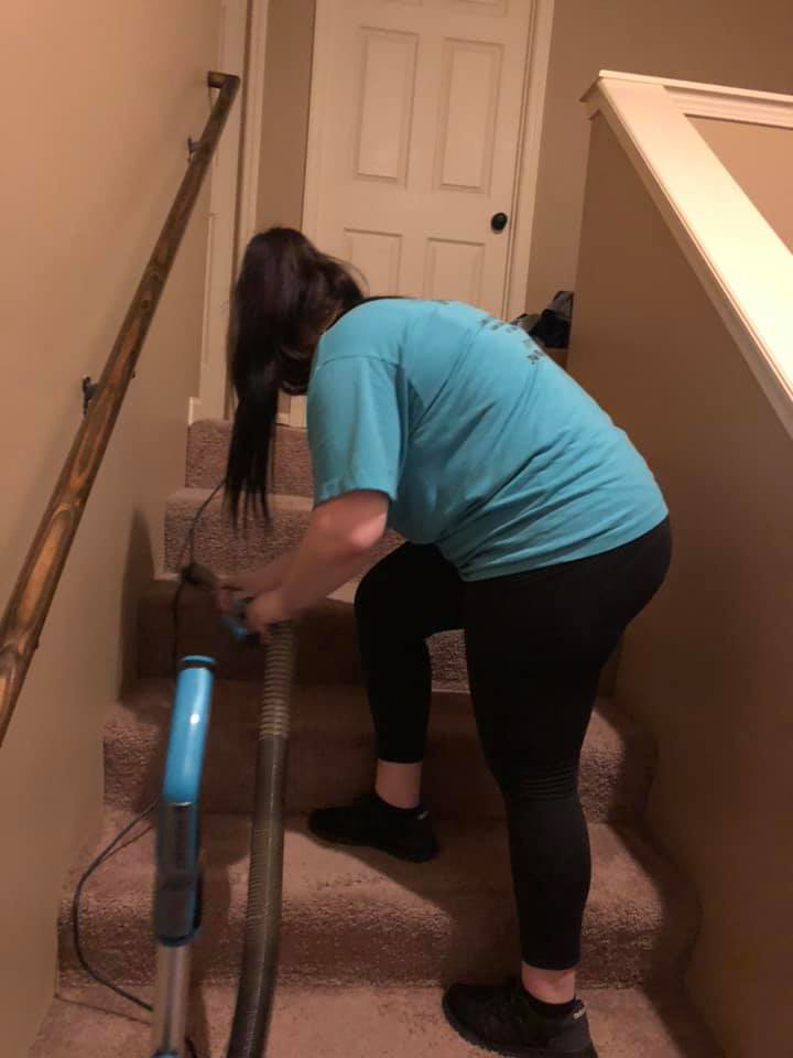 A cleaner from Bri and Sam's Cleaning Service vacuuming carpeted stairs in a home in Bonner Springs, KS.