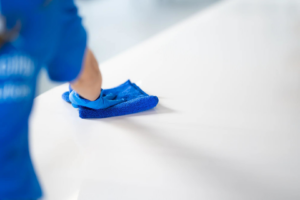 A person in blue gloves wiping a white surface with a microfiber cloth for Ultra Clean Carpet & Janitorial service in Carlsbad, NM.