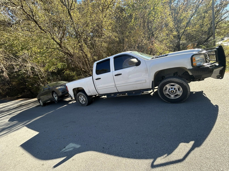 A white pickup tow truck from Jb's Towing & Recovery towing a dark sedan on a road in Rossville, GA.