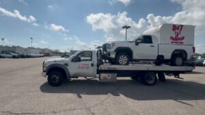 TJ Towing LLC flatbed truck towing a white pickup truck with a D&T Crawfish trailer in New Orleans, LA.