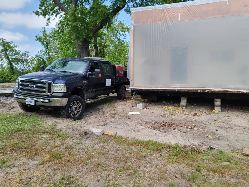 A pickup truck from Dyson's Mobile Repair & Hauling LLC towing a large portable building in Virginia Beach, VA.