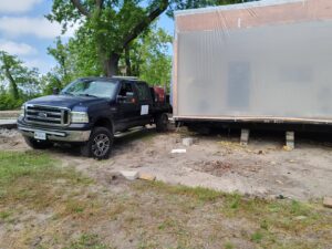A pickup truck from Dyson's Mobile Repair & Hauling LLC towing a large portable building in Virginia Beach, VA.