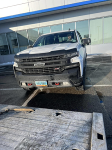 A white Chevrolet pickup truck positioned on a flatbed tow truck for service by Geely Towing in Fargo, ND.