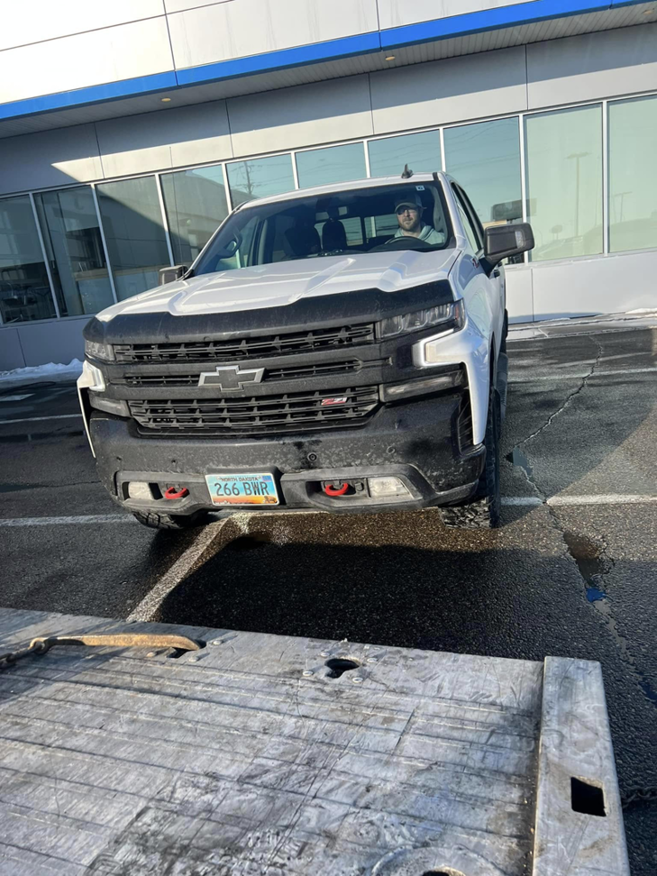 A white Chevrolet pickup truck positioned on a flatbed tow truck for service by Geely Towing in Fargo, ND.