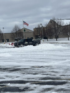 A pickup truck with a snow plow clearing a large parking lot, performed by Luna Landscape Pro in Racine, WI.
