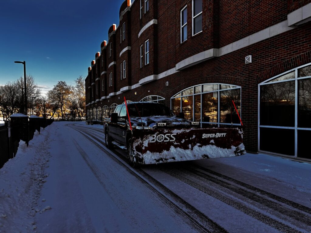 A pickup truck with a snow plow clearing a snowy driveway for 10.7 Property Solutions LLC in South Bend, IN