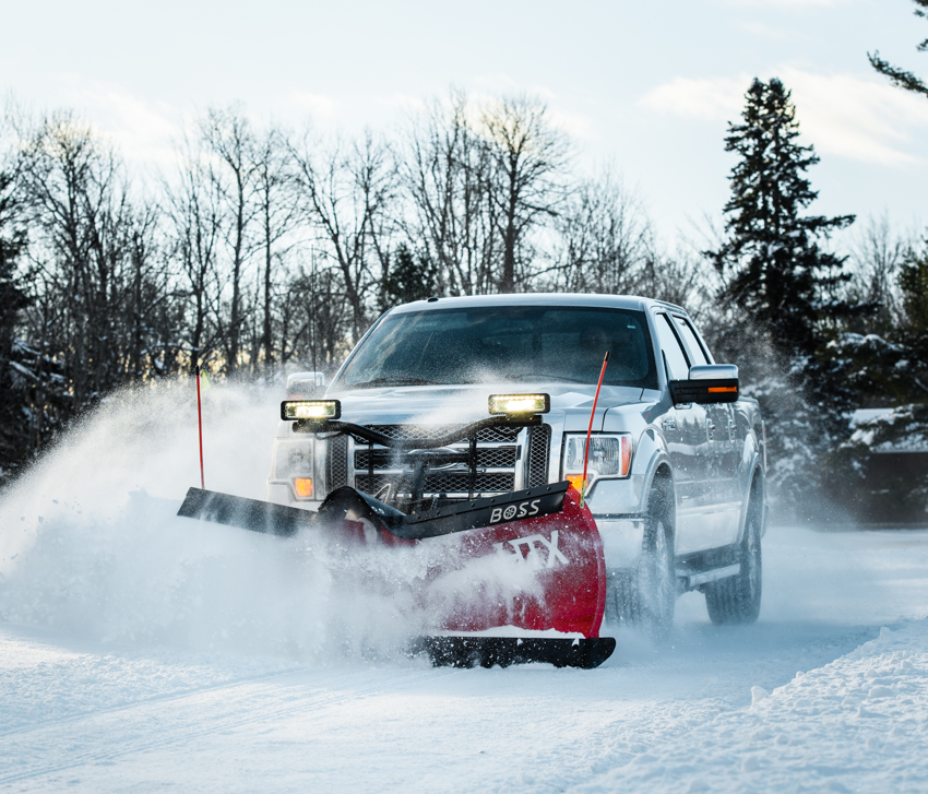 A silver pickup truck with a red snow plow actively clearing snow for Snow Removal St. Louis in St. Louis, MO.