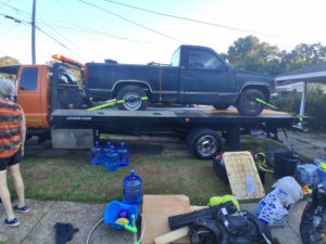 A dark pickup truck secured on a flatbed tow truck by AMC Towing in Mobile, AL.