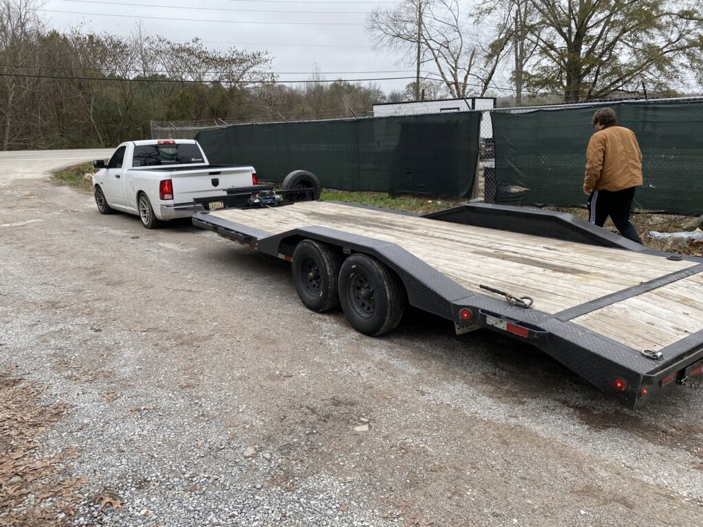 A white pickup truck hitched to an empty flatbed trailer from B'ham Trailer Rentals in Alabaster, AL.