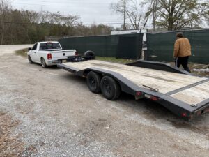 A white pickup truck hitched to an empty flatbed trailer from B'ham Trailer Rentals in Alabaster, AL.