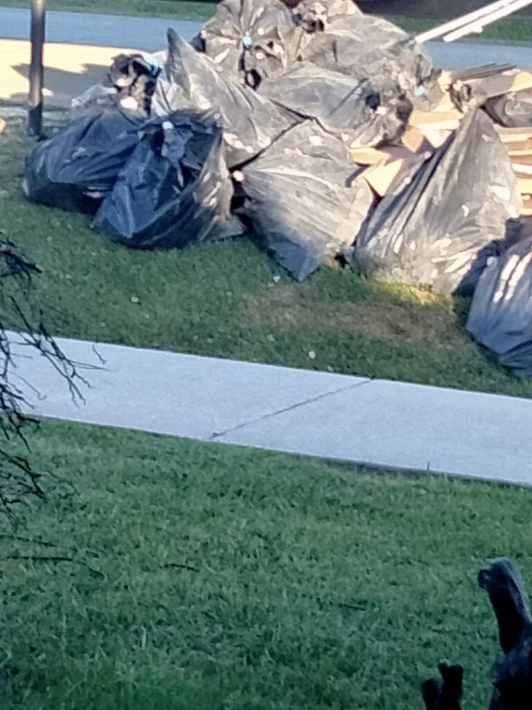 A large pile of demolition waste and debris, including black trash bags and wood, from a job by HaysCo Facilities Management, Inc. in Dothan, AL.