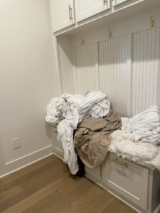 A pile of laundry on a bench, ready for professional cleaning and organization by Global Provisions, AR in Fayetteville, AR.