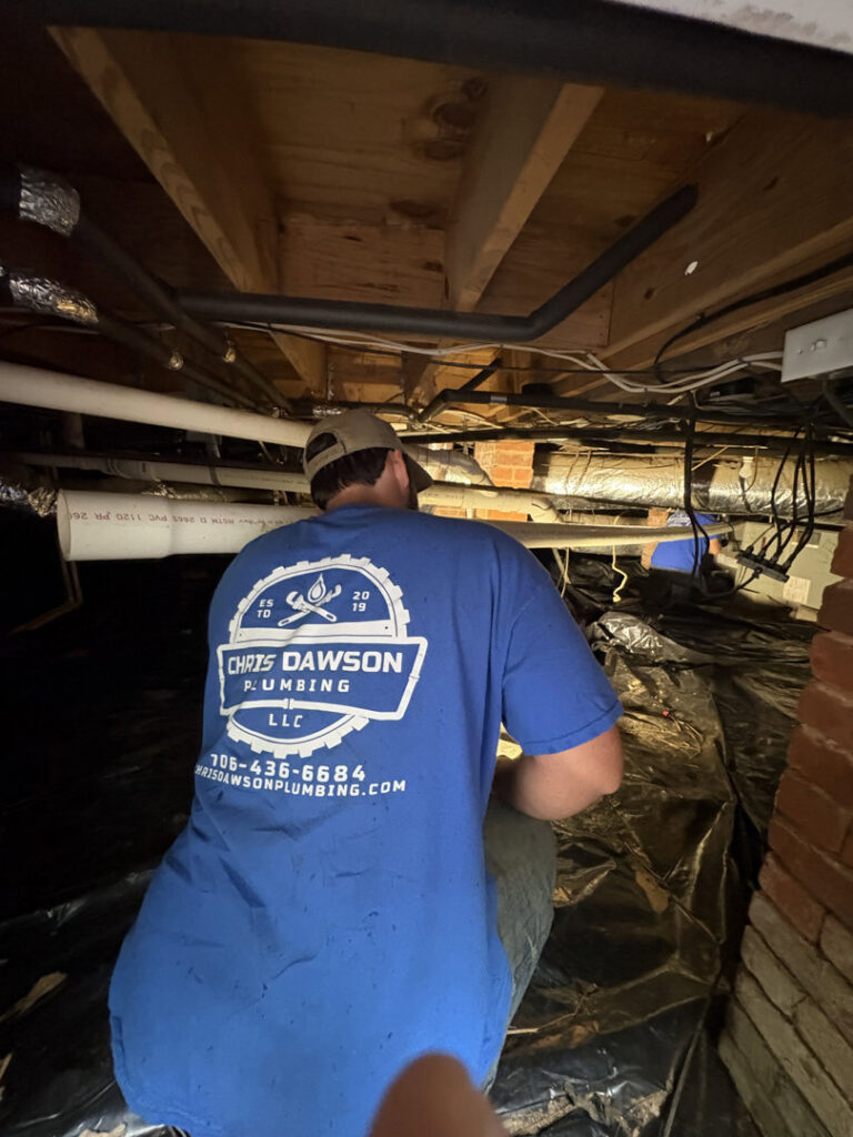 A plumber installing a vapor barrier in a crawl space for Chris Dawson Plumbing LLC and Septic System Specialist in Athens, GA.
