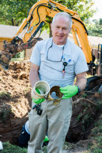 A plumber holding broken and corroded pipes, indicating water damage repair by Robert Brown Plumbing, LLC in Bossier City, LA.