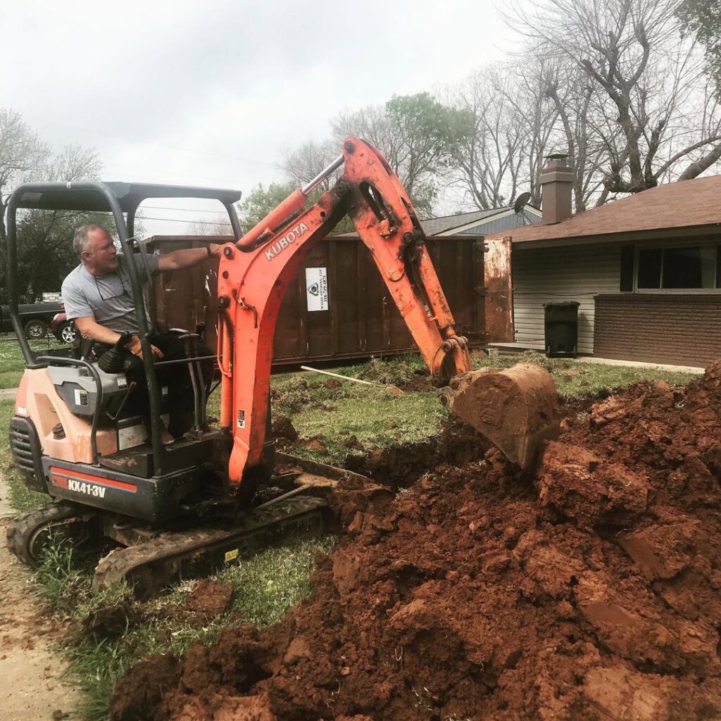 A plumber operating an excavator to dig a trench for pipe repair by Robert Brown Plumbing, LLC in Bossier City, LA.