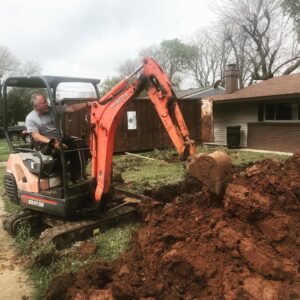 A plumber operating an excavator to dig a trench for pipe repair by Robert Brown Plumbing, LLC in Bossier City, LA.