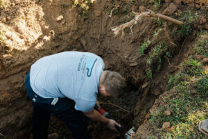 A plumber working in a trench on an underground pipe repair for Robert Brown Plumbing, LLC in Bossier City, LA.