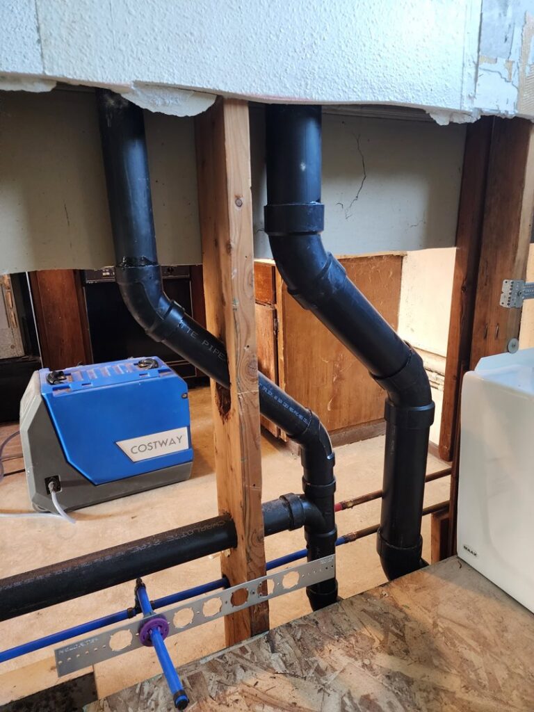 Exposed plumbing pipes and a blue dehumidifier used during water damage repair by A1 Restoration of Spokane in Post Falls, ID.