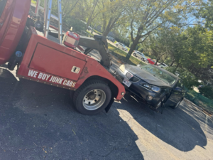 A PNB towing truck hauling a damaged dark sedan from a parking lot in Madison, WI.