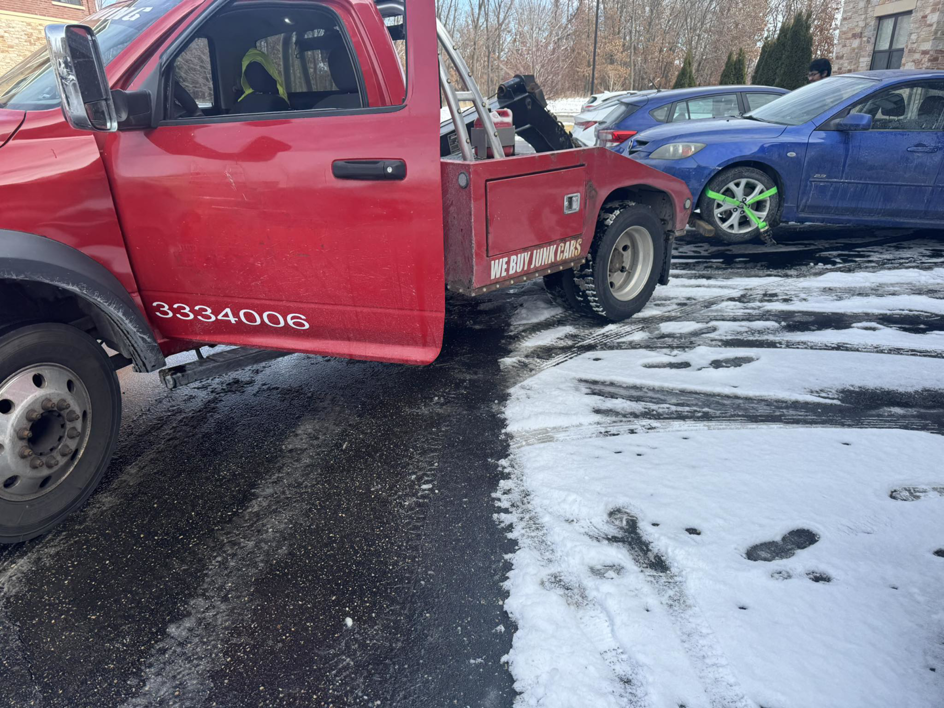 A PNB towing truck recovering a blue car from a snowy driveway in Madison, WI.