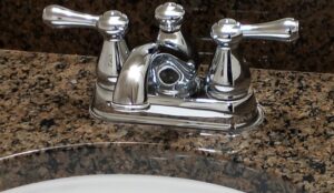 A polished chrome bathroom faucet and clean granite countertop, showcasing detailed cleaning by By Grace Cleaning Solutions, LLC in Cincinnati, OH.