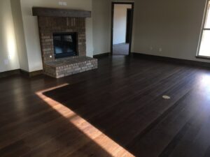 Gleaming, polished hardwood floors in a living room with a brick fireplace, cleaned by Pristine Cleaning Concepts in Stillwater, OK.