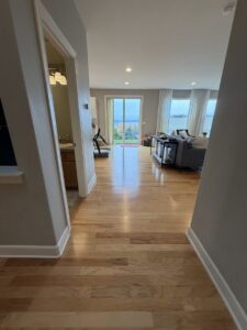 A polished hardwood hallway leading into a bright living room, showcasing the meticulous cleaning services of Quesada's cleaning services llc in Seattle, WA.