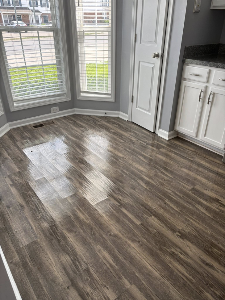 A beautifully polished wooden floor reflecting light in a room with bay windows, highlighting the floor cleaning expertise of Claudia's Cleaning Services in Clarksville, TN.