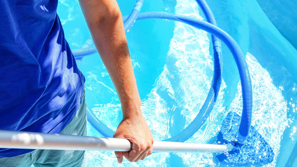 A pool cleaner brushing the pool walls and floor for Patriot Pool Cleaning Services in Naples, FL.