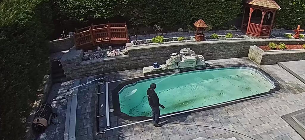 A pool cleaner from Coversafe, Inc. inspecting a dirty, green residential pool in Reno, NV.