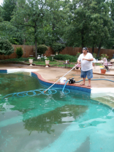 A pool cleaner actively vacuuming a very dirty green swimming pool for Danny's Pool Service in Stillwater, OK.