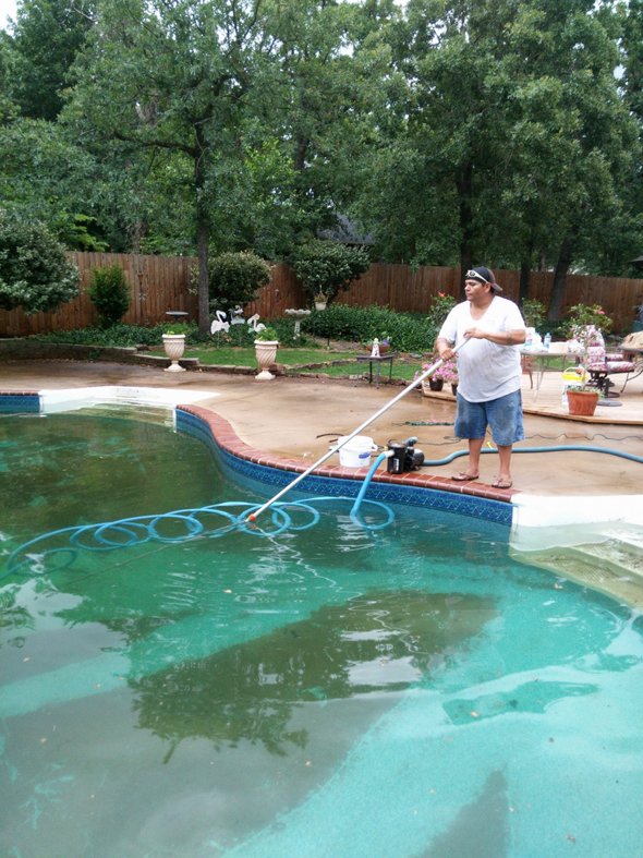 A pool cleaner actively vacuuming a very dirty green swimming pool for Danny's Pool Service in Stillwater, OK.