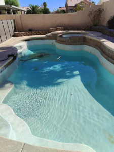 A pool cleaning vacuum hose visible in a residential pool by Suburban Pool Company in Germantown, WI.